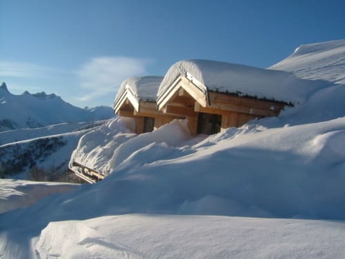 Snow-covered wooden chalets with mountain views at Chalet La Louvière in La Toussuire, French Alps