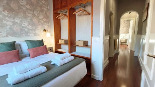 Dormitorio moderno en Mirador Medieval de Cáceres con armario de madera, almohadas coloridas, ropa de cama blanca y pisos de madera