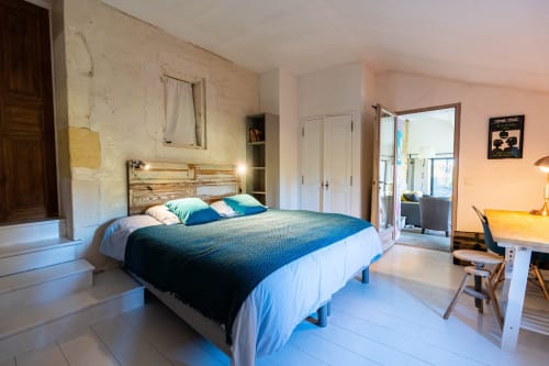 Chambre lumineuse au Mas F, Saint-Rémy-de-Provence, avec lit en bois, linge de lit bleu et portes ouvrant sur le jardin