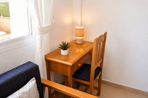 Escritorio de madera con silla, lámpara y planta en maceta en Apartamento Lateral Luz de Apartamentos El Calón Playa, Cuevas del