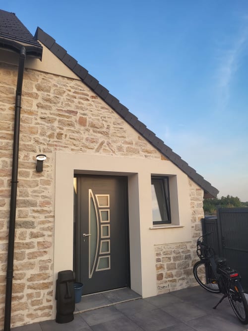 Entrée de la chambre d'hôtes Gîtes Les Camelias 71 à Oslon, France, façade en pierre et crème avec porte noire moderne