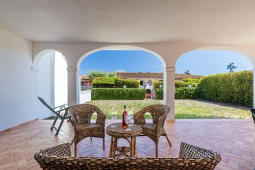 Poltrone intrecciate con tavolino sulla terrazza soleggiata dell'appartamento Youinsardinia a Bari Sardo, vista sul giardino