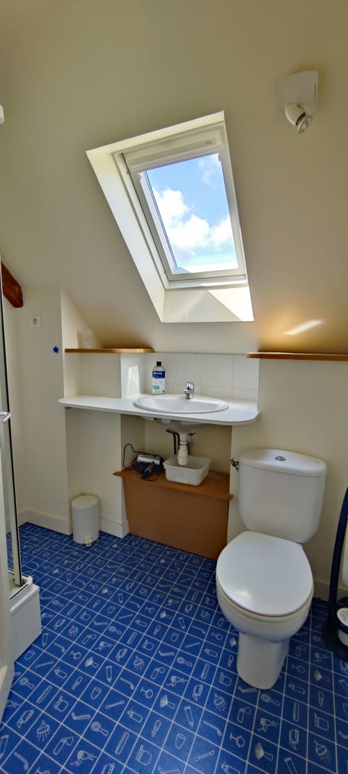 Salle de bains moderne avec puits de lumière, lavabo blanc, toilettes et carrelage bleu motifs à la villa Mer et Maisons à La Trinité sur Mer