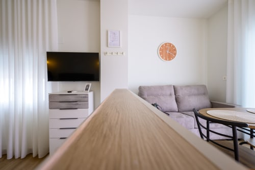 Apartamento estudio moderno en Hotel Alcazaba Salobreña con cama, sofá gris, televisor y reloj de pared redondo
