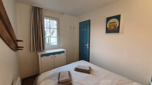 Cozy bedroom at Ô CAP COZ apartment in La Fôret-Fouesnant with bed, teal door, window, and sea view décor