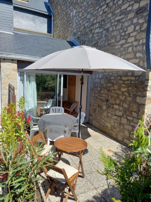 Coin détente en terrasse à Mer et Maisons, La Trinité sur Mer, avec parasol, table bois et vue jardin