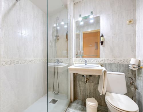 Baño moderno con ducha, lavabo e inodoro en el Hostal El Molino de Collado Villalba, España