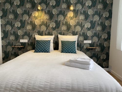 Chambre de l'appartement La Maison Blanche avec papier peint botanique, literie blanche et coussins à motifs sombres à Bouguenais
