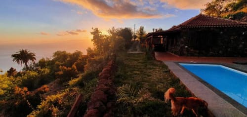 Vista del atardecer desde la terraza de Villa El Topo con piscina privada, vistas al océano y villa de tejas rojas frente a El Pinillo, La Palma