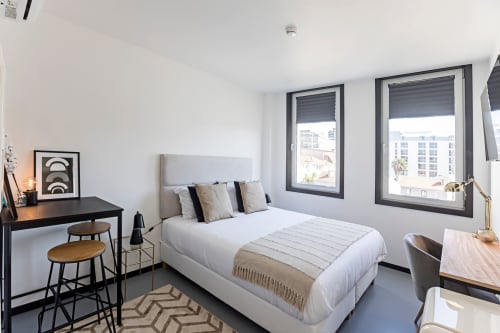 Quarto estúdio moderno e compacto no hotel do Porto com cama queen, escrivaninha, grandes janelas com vista para a cidade e design contemporâneo