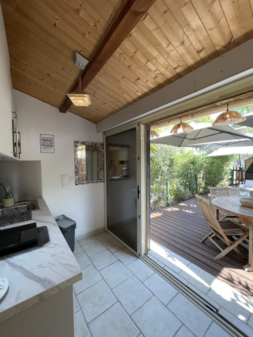 Cuisine moderne ouvrant sur terrasse en bois avec vue sur le jardin, appartement La Montagnette à Cap d'Agde, France
