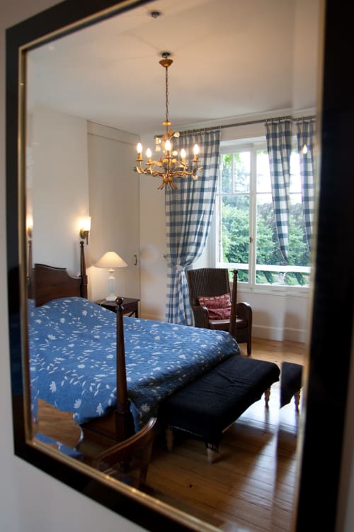 Chambre élégante aux Chambres d'hôtes Les Pratges à Figeac avec lit à motifs bleus, lustre en laiton et grandes fenêtres