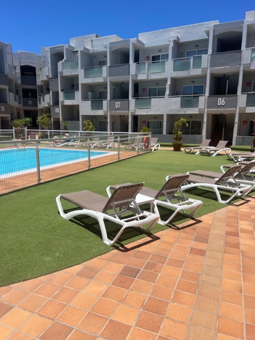 Pool view at FTV Holidays Homes apartment in Corralejo with lounge chairs and modern building