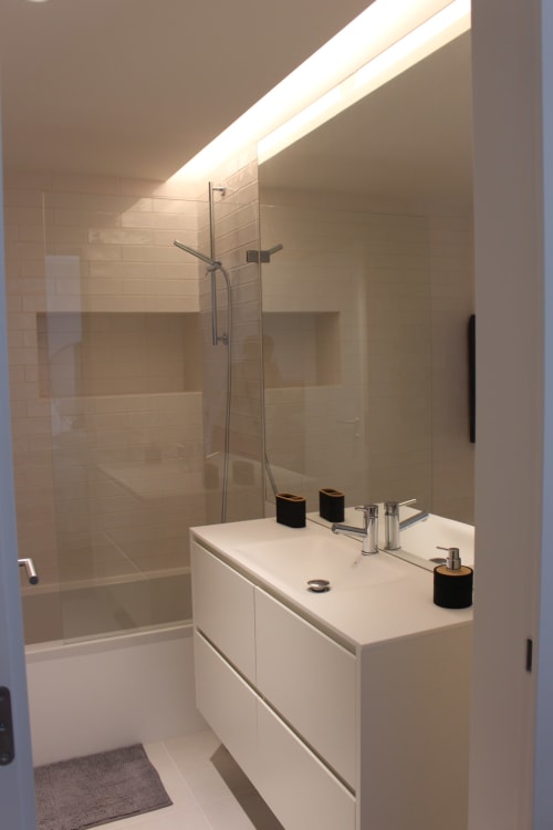 Modern bathroom at Break Lovers Tavira with sleek white vanity, glass shower enclosure, and skylight