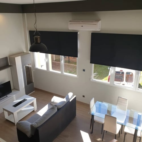 Moderna sala de estar en Hostal El Molino con sofá, mesa de comedor y grandes ventanas con cortinas blackout