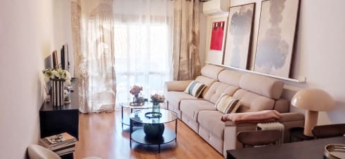 Moderno salón en Fuengirola con sofá beige, mesa de café de cristal y vistas a la ciudad desde las puertas de la terraza