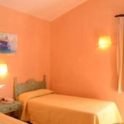 Dormitorio naranja brillante con cama, mesilla de noche e iluminación cálida en Las Golondrinas Apartamentos Turísticos en Cap d'Artrutx