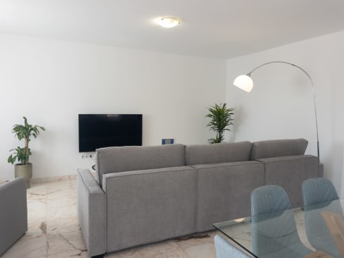 Modern villa living room with gray sofa, arc lamp, and Smart TV at FTV Holidays Homes in Geafond, Spain