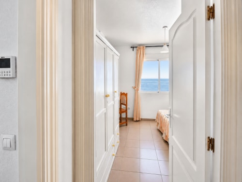 Luminoso pasillo con puertas blancas, cortinas a rayas y vistas al mar en apartamento frente a playa de El Calón Playa, Cuevas del