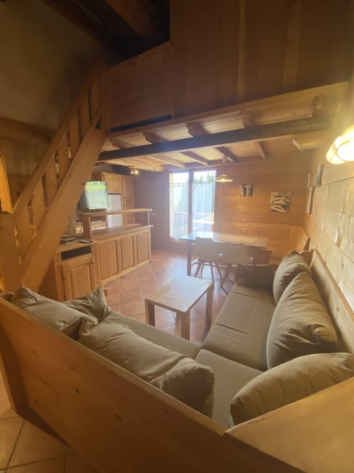 Séjour spacieux et ouvert avec poutres apparentes, cuisine, table à manger et coins détente à La Ferme des