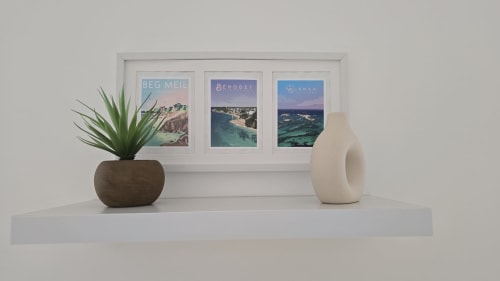 Modern apartment shelf with travel posters of Breton coastal destinations, potted succulent, and white ceramic vase
