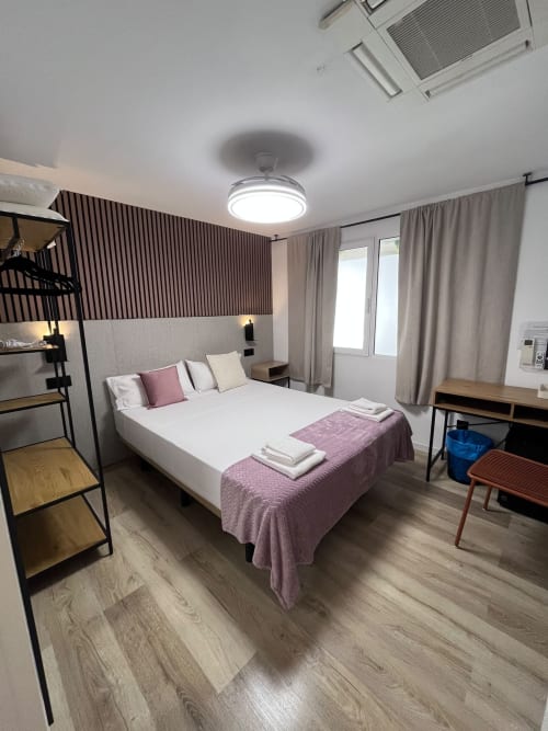 Habitación estándar moderna en Hostal Abacoa en Alicante con cama queen, escritorio, loft y vistas a la ciudad