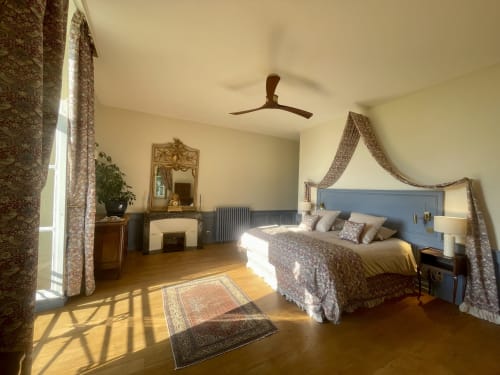 Chambre élégante au Château de Vaux Morvan avec lit à baldaquin, ventilateur de plafond et vue sur le jardin à Étang sur Arroux