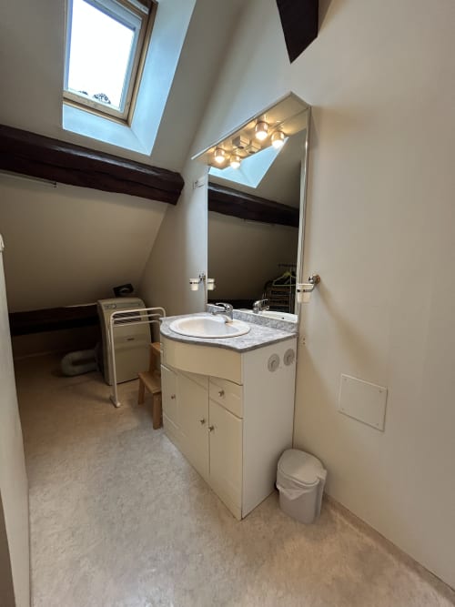 Salle de bains moderne dans l'appartement Le Duplex 1 à Hébergement Luxeuil Les Bains avec vasque, miroir, toilettes et puits de lumière