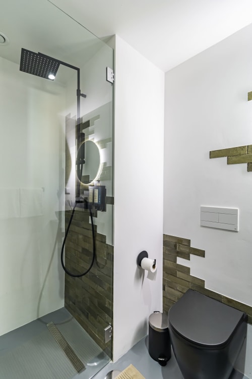 Banheiro moderno no estúdio Benefit Collection Porto com chuveiro tipo chuva, espelho iluminado e metais pretos