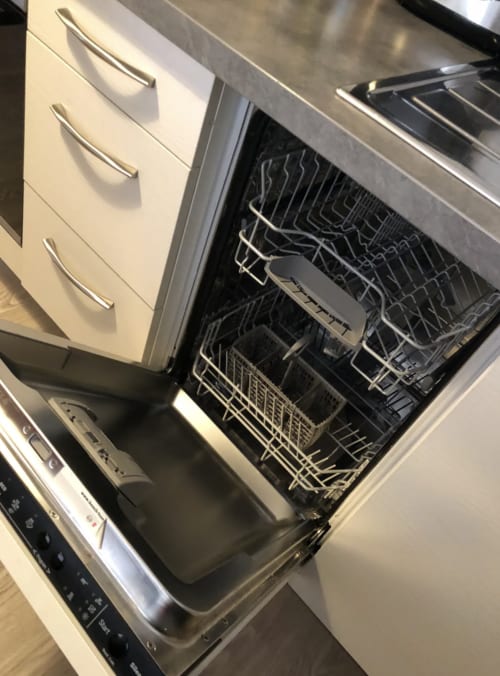 Lave-vaisselle ouvert avec ses bacs dans la cuisine moderne de l'appartement Le Paillot de Montabert à Troyes