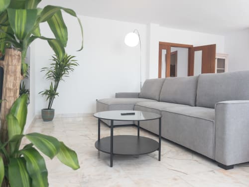 Modern living room in Casa Reguera villa at FTV Holidays Homes with gray sofa, round table, plants, and sea view
