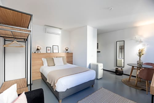 Studio Standard luminoso da Coleção Benefit Porto com cabeceira de madeira, roupa de cama branca, área de refeições e kitchenete