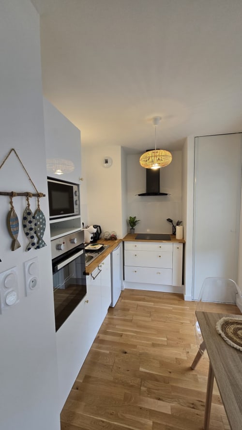 Modern kitchen with white cabinetry, wooden counters, and pendant lighting in Ô KASTEL apartment at Location Vacances