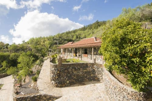 Villa Awara en El Pinillo, La Palma con tejado de terracota, muros de piedra, vistas de montaña, jardines exuberantes y patio exterior
