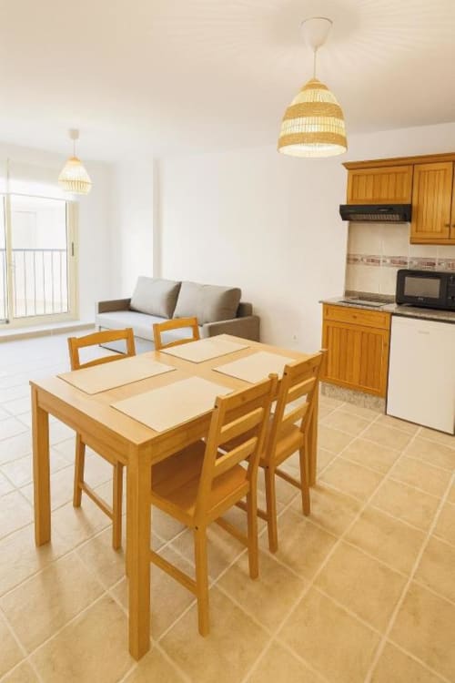 Cocina y comedor abiertos con mesa de madera, sillas y electrodomésticos en apartamento El Remo, La Palma