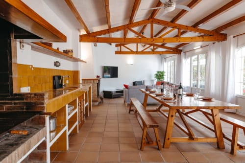 Cocina y comedor abiertos con vigas de madera, detalles en azulejos amarillos y vistas al jardín de Las Golondrinas, Cap