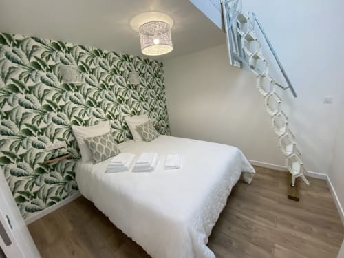 Modern bedroom at La Maison Blanche B&B in Bouguenais with botanical wallpaper, white bedding, and contemporary decor