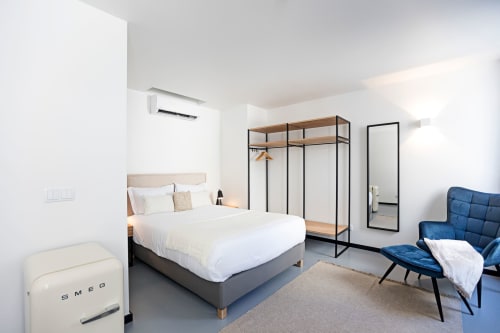 Studio moderno no Porto com cama, poltrona azul, kitchenette, guarda-roupa e vista para a cidade