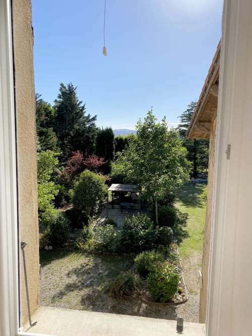 Vue du jardin du gîte Le Papillon au Cocon De Curson à Chanos-Curson, avec verdure luxuriante et montagnes lointaines