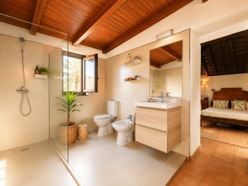 Salle de bains moderne à l'appartement Casa Miranda, Corralejo, avec douche à l'italienne, meuble vasque en bois, toilettes, bidet et lumière naturelle