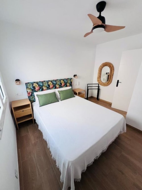 Dormitorio moderno en El HierroStay Apartments en La Restinga con cama queen, almohadas verdes, mesitas de noche de madera y ventilador de techo