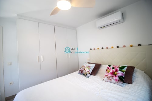Casa LirioBlanco en dormitorio moderno de la casita de setenil de las bodegas con cama blanca, cabecero crema y almohadas floreadas