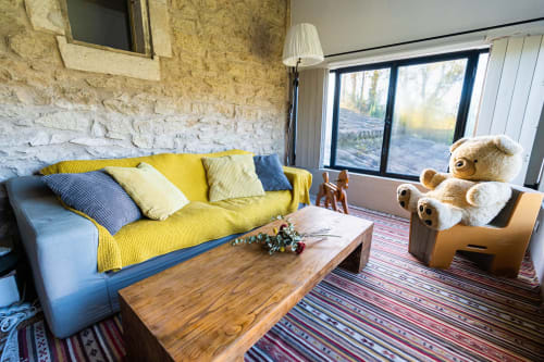 Séjour lumineux au Mas F avec canapé jaune, table en bois et vue sur le jardin à Saint-Rémy-de-Provence