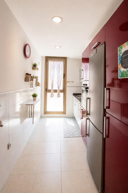 Cuisine moderne de l'appartement Sara & Gino à Fuerteventura avec meubles blancs, accents bordeaux et appareils inox