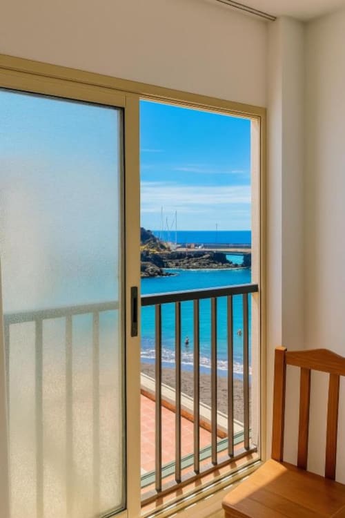 Vista desde el balcón del apartamento El Remo en La Restinga con vistas al océano turquesa, playa y puente costero bajo cielo azul