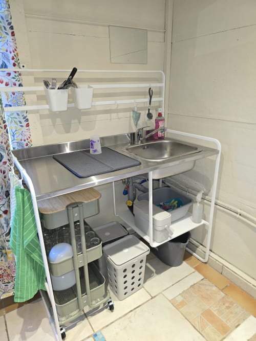 Petite kitchenette équipée dans un cottage de micro-camping au Domaine Trianon avec évier, cuisinière, rangements et accessoires organisés
