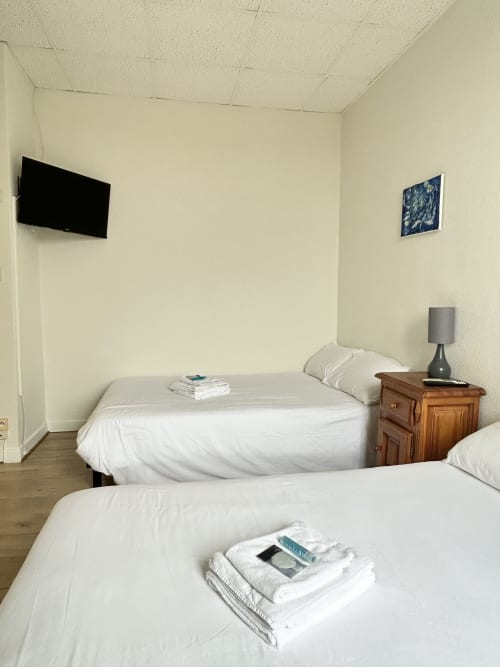 Deux lits jumeaux avec draps et serviettes blancs dans une chambre quadruple lumineuse à l'hôtel BDM à Montastruc-la-Conseillère, France