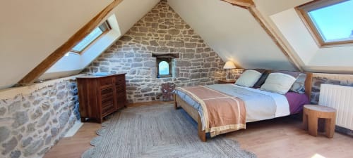 Chambre mansardée à la villa Mer et Maisons avec murs en pierre, poutres apparentes, lucarne et vue sur le jardin à La Trinité-sur-Mer