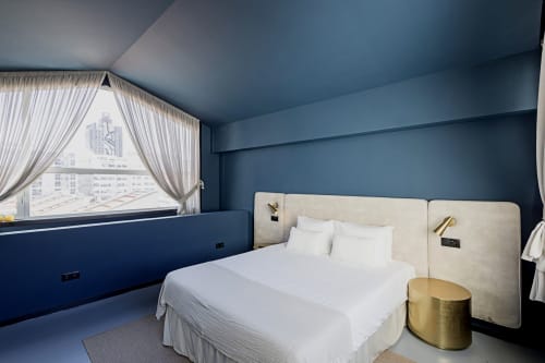 Quarto moderno de hotel no Porto com cama creme, paredes azuis, vista para a cidade e detalhes em ouro no estúdio duplex Benefit Collection