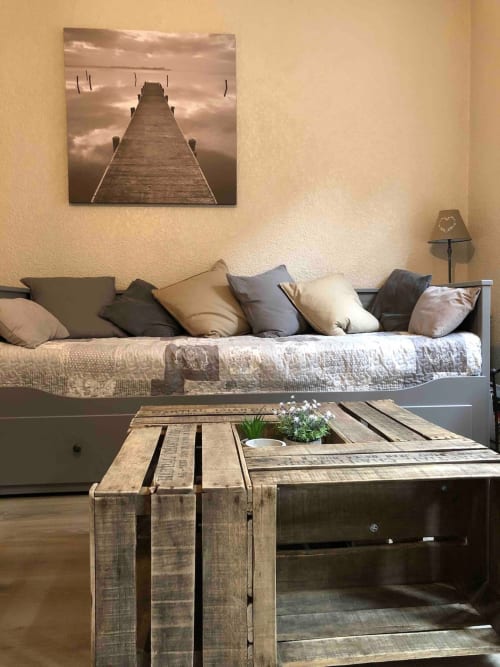 Salon cozy de l'appartement Le Paillot de Montabert à Troyes avec canapé, table en bois et tableau de pont encadré.